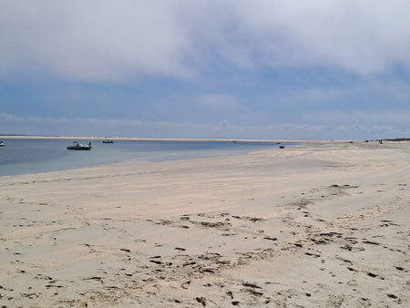 Beach at low tide with boats in the background on a sunny dayの写真素材