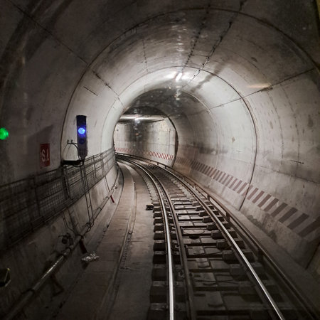 A detailed photograph of an underground railway tunnel featuring multiple train tracks, concrete walls, and industrial lighting.の写真素材