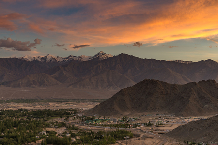 dramatic colorful sunset with mountains cover with snow and small city below Dramatic overcast sky. Leh, Ladakh, India.  Everest rang mountains. Beauty world.の写真素材
