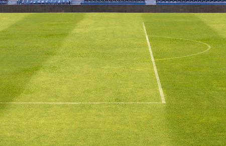 green grass from football field, soccer field with shadow of grandstandの写真素材