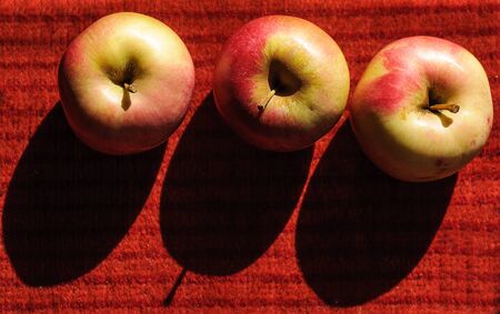 Three ripe apples on the red carpet.