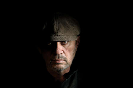 Portrait of elderly man in black clothes on a black background.