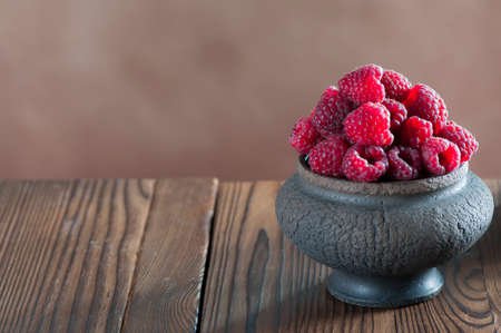 Still life with ripe raspberries in a ceramic vaseの写真素材