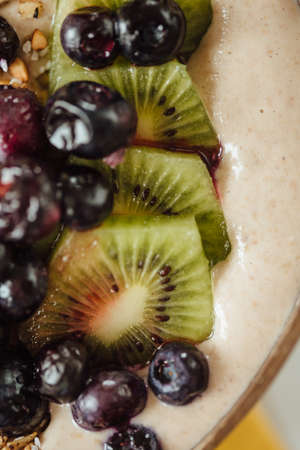 Homemade granola with nuts and raisins, kiwi, blueberries on oatmeal. Top view. Idea of healthy...