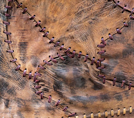 Leather patchwork. Pieces of leather stitched together with coarse threads.の写真素材