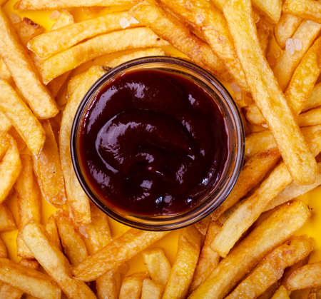 The ketchup is on the fries. Yellow bright background. Food background. View from above.の写真素材