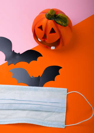 Pumpkin, bats and a medical mask on a bright background. Halloween during the covid-19 pandemic.の写真素材