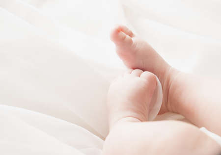 Feet of a newborn baby on an airy white background. Close-up.