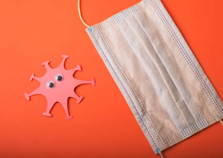 Coronavirus and medical mask on the second wave. Made from paper. Bright background. Free space.の写真素材