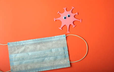 Coronavirus and medical mask on the second wave. Made from paper. Bright background. Free space.の写真素材