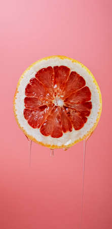 Ripe orange grapefruit cut in half and dripping with juice on a bright background. Close-up.の写真素材