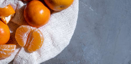 Tangerines lie on a white fabric and a gray textured background with free space on the right. View from above. Hard light.の写真素材