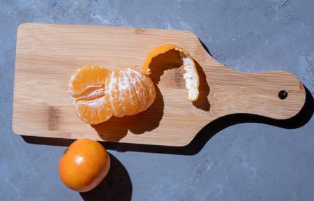 Tangerines on a gray textured background and a wooden board. View from above. Hard light.の写真素材
