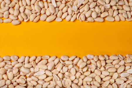 Peanuts on a yellow background with a free space in the middle. The view from the top.の写真素材