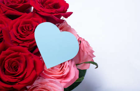 Bouquet of beautiful roses with a card in the form of a heart. Valentine's day gift. White blank background. Place for your text.の写真素材
