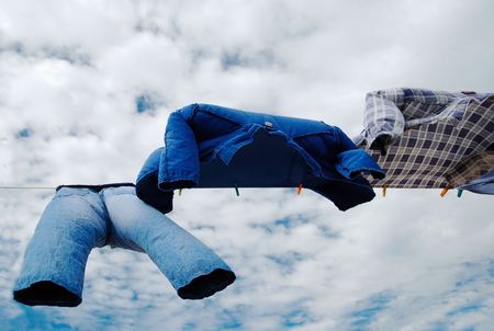 Drying trousers and shirts on wind over cloudy skyの写真素材