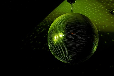 Disco ball in motion reflecting green light in night club with copy-spaceの写真素材