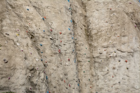 Structure of artificial rock-textured wall with coloured handholds and feetholds