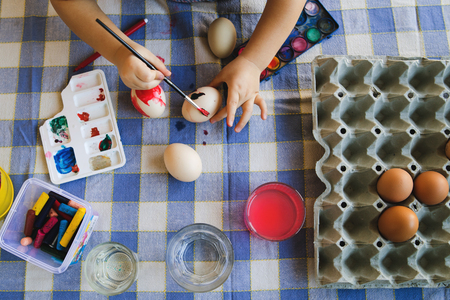High angle View on little boy painting Easter Eggs at homeの写真素材