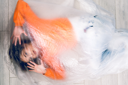 Young woman wrapped in nylon transparent bag trapped frustrated freedom human trafficking conceptの写真素材
