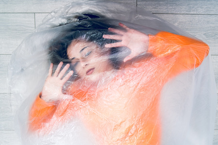 Young woman wrapped in nylon transparent bag trapped frustrated freedom human trafficking conceptの写真素材