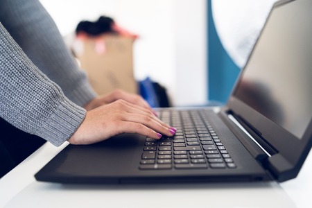 Close Up on woman's hands woman using laptop on the white table typing on the black keyboard at work...