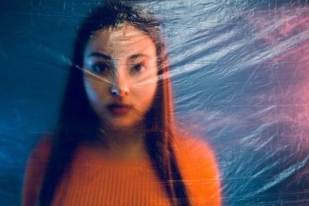 Portrait of teenage girl trapped behind the plastic nylon foil, human rights antipollution trafficking conceptの写真素材