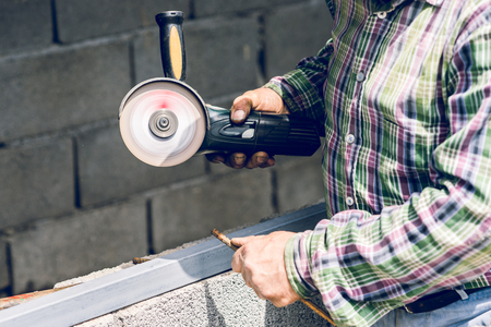 Close up on man using grinder to cut metal bar at the construction siteの写真素材