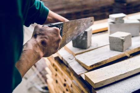 Close up on the construction worker using the hand saw to manually cut the brick insulation material concrete stoneの写真素材
