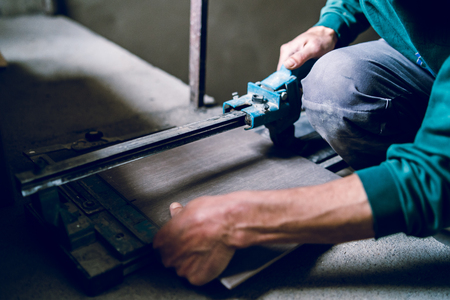 Close up on construction worker craftsman using tool for cutting ceramic tiles for laying installation to the bathroomの写真素材