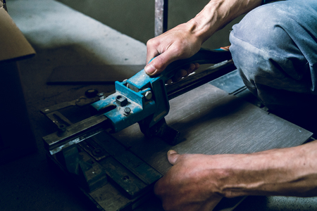Close up on construction worker craftsman using tool for cutting ceramic tiles for laying installation to the bathroomの写真素材