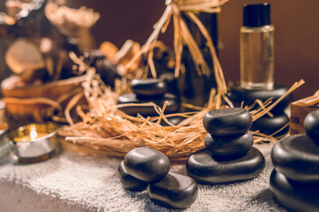 Spa essential aromatic oil in vintage bottle and massage basalt zen stones and candles on the tableの写真素材