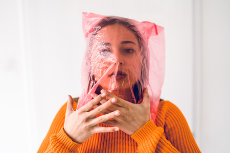 Young woman with plastic bag on her head choking, antipollution save the planet concept anti plastic...