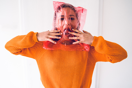 Young woman with plastic bag on her head choking, antipollution save the planet concept anti plastic pollution campaignの写真素材