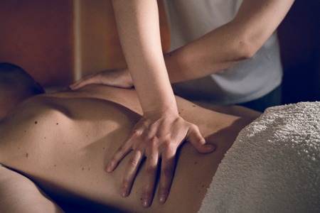 Young woman female massage therapist giving massaging relax sport to young athlete at spa studioの写真素材