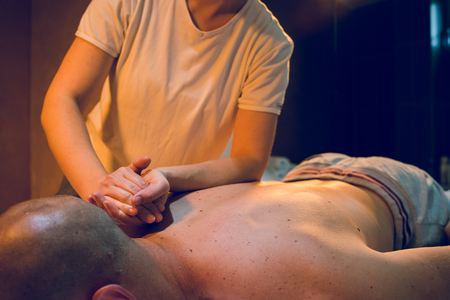 Young woman female massage therapist giving massaging relax sport to young athlete at spa studio arm handの写真素材