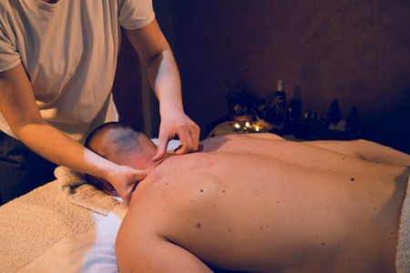 Young woman female massage therapist giving professional massaging relax sport to young athlete at spa studioの写真素材