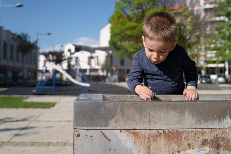 Little boy at the public fountain playing with water drinking in summer sunny dayの写真素材