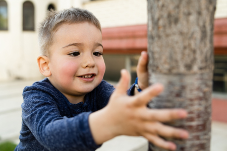 Small boy holding a tree at the city squareの写真素材