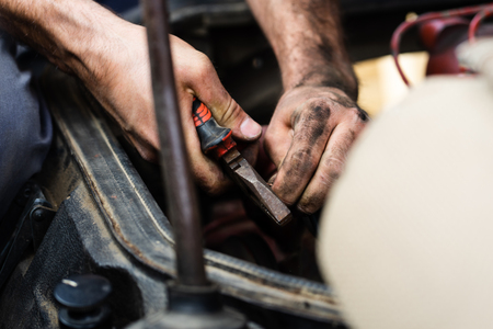 Close up on mechanic repair man electrician using hand tool combined pliers to connect copper wires on the motor engine block of the truckの写真素材