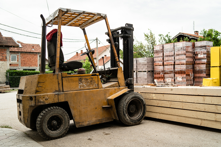 Fork lifter holding a stack of rough sawn timber pine lumber construction material at the building siteの写真素材
