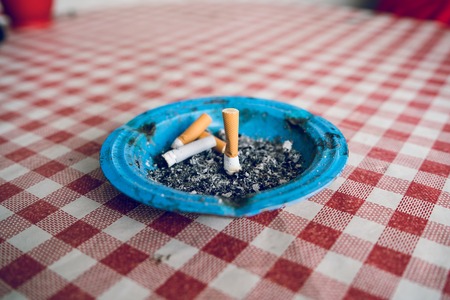 Cigarette butt end stubs in the ash tray on the table quitting smoke health lungの写真素材