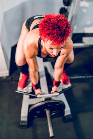 Muscular woman female athlete work out at the gym training using T-bar rowing back workout bodybuilding fitnessの写真素材