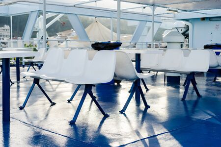Side view on the seats with table on the deck of the ferryboat on the seaside travel ship
