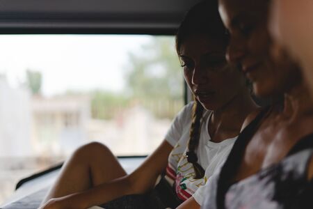 Young woman sitting in a bus public transportation smiling in shadowの写真素材