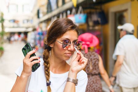 Young pretty beautiful woman trying sunglasses on the street store in a summer dayの写真素材