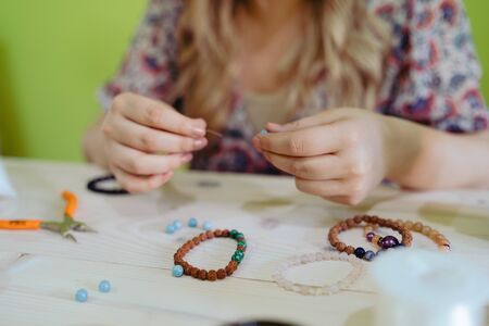 Young woman making crystal jewelery necklace and bracelet at home manuallyの写真素材