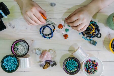 High angle view of Young woman making crystal jewelery necklace and bracelet at home manuallyの写真素材