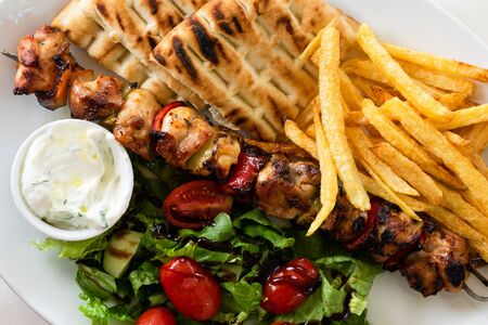 High angle view on souvlaki on skewer greece meal food with fried potato chips vegetables and homemade pita breadの写真素材