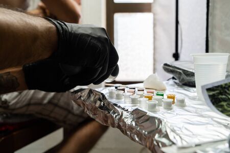 Professional tattoo artist preparing machine colors mix for artwork at studio saloon tattooingの写真素材